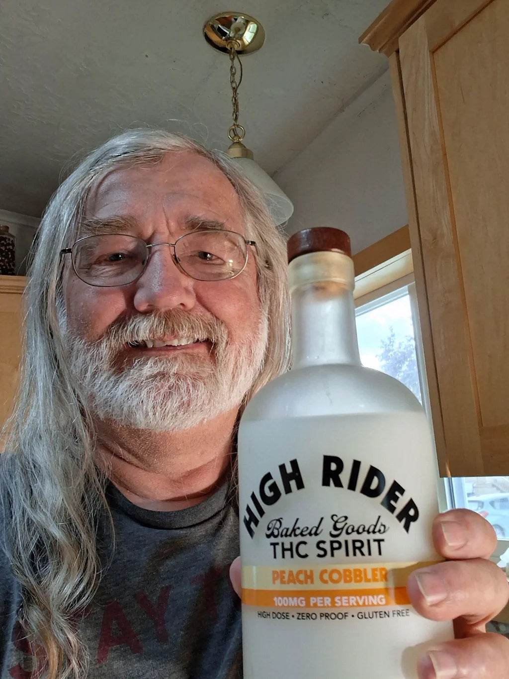 Dan holding a High Rider Peach Cobbler THC Spirit bottle